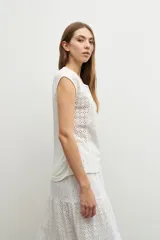 Blusa blanca con bordado calado, de corte recto y mangas cortas.