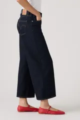 Jean de denim azul oscuro con corte wide leg y diseño cropped al tobillo, con tiro medio y costuras en contraste.