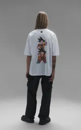 Remera blanca de corte oversize con cuello redondo y mangas cortas. Presenta un estampado central en la espalda con los personajes Goku y Goten de Dragon Ball.