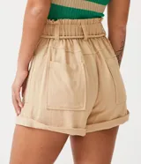 Short color beige de viscosa y lino, corte clochard, con cinturón de cuerda con borlas, bolsillos laterales y ruedo doblado.