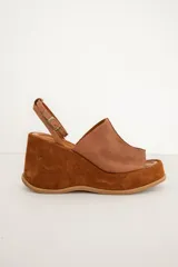 Sandalia de plataforma corrida de cuero marrón, con capellada ancha y tira fina ajustable al tobillo con hebilla metálica.