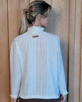 Camisa de manga larga con estampado de rayas verticales en tonos crudo y beige. Presenta cuello alto con volados, cierre frontal con botones dobles y puños con volados.