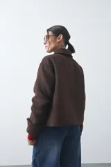 Tapado corto de paño con textura, color marrón, de corte recto y silueta estructurada. Presenta cuello camisero, cierre frontal con botones grandes y mangas largas con detalle de trabas en los puños.