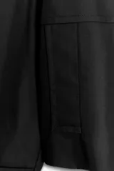 Trench corto negro confeccionado en hilatura con mezcla de algodón. Cuello solapa de muescas ajustable con trabilla y botones. Manga larga. Bolsillos delanteros. Detalle de trabillas en hombros. Cierre frontal cruzado con botones.