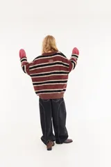 Sweater de textura peluda con diseño de rayas horizontales en tonos bordó, amarillo y azul. Presenta un corte holgado, cuello redondo y un pequeño logo bordado en el centro del pecho.