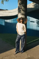 Pantalón de tiro medio con cintura elástica y bolsillos ocultos en costura. Presenta un diseño de corte recto con dobladillo ancho en el bajo y un estampado geométrico sobre fondo oscuro.