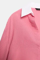 Camisa de rayas finas color rosado, con cuello solapa y puños largos en color blanco a contraste. Presenta cierre frontal con botones y bajo asimétrico con aberturas laterales.