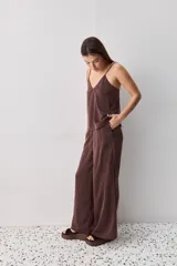 Pantalón wide leg de tiro medio y calce amplio, color marrón, con pinzas delanteras, cierre frontal y bolsillos laterales funcionales.