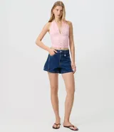 Short de jean azul oscuro con corte evasé, bolsillos delanteros y traseros, pasacintos en la cintura y cierre frontal con botón y cremallera. Incluye un pequeño aplique metálico de corazón.