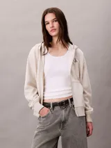 Buzo con capucha, cierre frontal de cremallera y bolsillos canguro, de color beige, con logo monograma de Calvin Klein bordado en el pecho.