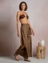 Pantalón palazzo de lino color azul, de tiro alto con cintura elastizada y cinto lazo incorporado con cuentas decorativas en las puntas. Presenta aberturas laterales pronunciadas en las piernas y corte amplio.