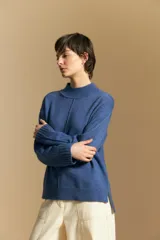 Polera de tejido de punto color blanco, con cuello alto acanalado, hombros caídos y detalle de costura vertical en el frente.