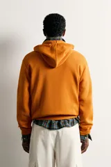 Sudadera con capucha y cierre frontal de cremallera, de corte relaxed fit, confeccionada en tejido de algodón con estructura waffle en color naranja. Cuenta con bolsillos frontales de vivo, cordones ajustables blancos y acabados en rib.