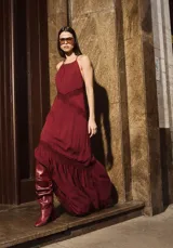 Vestido largo color bordó con cuello halter, detalle de encaje en la cintura y en el ruedo, y falda con volado inferior.