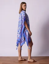 Kimono tejido con estampado abstracto en tonos azules, blancos y violetas. Tiene terminación de ruedo con borlas.