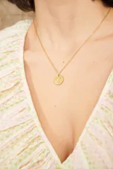 Cadena dorada fina con dije redondo con la imagen de una reina.