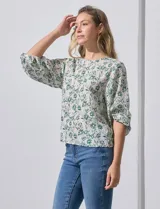 Blusa de gasa con estampado geométrico en tonos negro, gris y celeste. Tiene cuello redondo y mangas 3/4 amplias con abertura y botón.