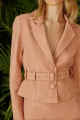 Blazer color salmón de tweed con cuello de solapa, corte entallado, cierre frontal con botón y cinturón con hebilla.
