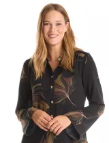 Camisa de crepe con estampado floral en tonos verdes y marrones, cuello con solapa, cierre frontal con botones y detalle de mostacillas bordadas en los hombros. Presenta mangas largas con terminación amplia.
