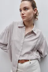 Camisa de viscosa color celeste, de calce amplio y caída fluida, con cuello clásico, cierre frontal de botones y detalles calados en mangas y delantero.