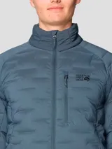 Campera técnica acolchada de plumón, color azul, con cierre frontal de dos vías, cuello alto, bolsillo en el pecho con cierre y bolsillos laterales. Presenta una construcción elástica tejida que permite mayor libertad de movimiento.