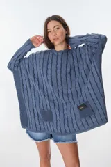Sweater de tejido de punto con diseño de ochos, color beige, de corte holgado y manga larga con puños ajustados. Presenta dos bolsillos frontales tipo parche con detalle de etiqueta de cuero.