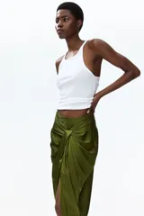 Pollera midi de satén color verde militar, con diseño cruzado, detalle drapeado frontal y tajo pronunciado.
