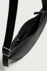 Bolso de hombro pequeño color negro con acabado liso, diseño semilunar y costura central. Cuenta con compartimento principal con cierre de cremallera, bolsillo interior con cierre y asa de hombro ajustable con hebilla.