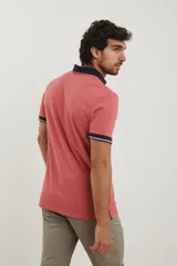 Remera tipo polo de manga corta, color azul marino jaspeado, con cuello y ribetes en las mangas de color azul oscuro y blanco.