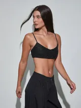 Top negro de tirantes finos con textura y apliques brillantes, escote redondo y diseño corto.
