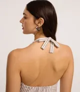 Blusa de jeans con cuello halter y escote en V, diseño a rayas verticales en color beige y blanco. Presenta cierre frontal con botones forrados y lazo para atar al cuello.