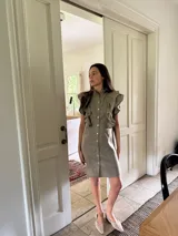 Vestido corto color verde oliva de lino con cuello mao fruncido, volados en los hombros, caída recta y botones al frente.