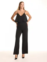 Enterito negro de crepe con escote en V, breteles finos ajustables y una capa suelta en la parte superior. La cintura es definida con corte anatómico y el pantalón tiene pierna ancha de caída fluida. Cierre invisible en la espalda.