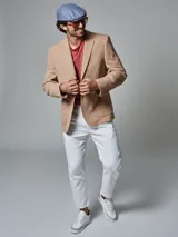 Saco color beige de piqué con cuello con solapas y bolsillos de plastrón. Mangas con coderas y bajo con abertura en espalda.