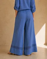 Pantalón azul de corte ancho y relajado, confeccionado en lino, con detalle de tejidoado geométrico en el ruedo.