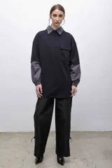 Remerón negro con cuello camisero, mangas largas con puños elásticos y bolsillo con solapa en el pecho.