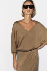 Vestido midi de punto color marrón con escote en V, mangas anchas y diseño holgado. Incluye un cinturón delgado marrón con hebilla metálica.