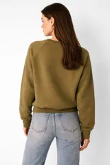 Sudadera negra de cuello redondo, manga larga tipo raglán y corte holgado.