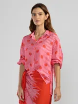 Camisa de manga larga color rosa con rayas verticales rojas y estampado de flores rojas. Con cuello camisero, puños elastizados y lazos regulables en los costados del ruedo.