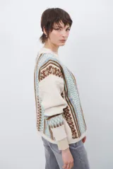 Cardigan de punto con escote en V y cierre frontal de botones. Presenta un diseño estampado con patrones geométricos en tonos beige, marrón y detalles en azul vibrante.