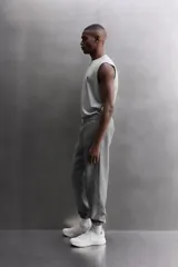 Pantalón jogger gris de corte regular fit, confeccionado en tejido de algodón con interior afelpado. Cuenta con cintura elástica ajustable con cordón, bolsillos laterales de vivo y traseros de plastrón. Presenta un texto estampado en color bordó en la pernera y bajo acabado en puño con elástico. Incluye un parche con logo combinado a contraste en la cintura.