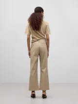 Pantalón tobillero color beige, de corte flare y tiro alto.