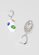 Par de aros colgantes con base de metal dorada, aro superior tipo argolla y dije ovalado de loza blanca con incrustaciones de piedras de colores: verde, azul y marrón.