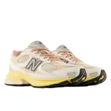 Championes urbanos New Balance modelo 2010, con diseño en tonos beige, crema y amarillo. Presenta una combinación de malla y gamuza en el exterior, con el logo N característico en el lateral y una suela de goma con entresuela amarilla destacada.