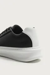 Zapatilla deportiva de diseño minimalista, confeccionada en material sintético negro con suela de plataforma blanca y detalle de contraste en el talón.