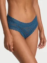 Panty tipo cheeky de tiro bajo confeccionado íntegramente en encaje azul, con bordes festoneados y cobertura trasera mínima.