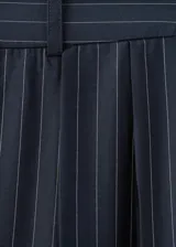 Pantalón azul marino de tiro alto con sutiles rayas diplomáticas blancas, de corte amplio y fluido con bolsillos laterales.