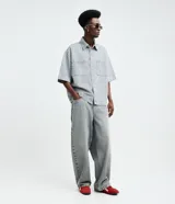 Pantalón de jean estilo baggy balloon, de corte holgado con volumen en las piernas y cintura fija con trabillas. Presenta un diseño clásico de cinco bolsillos y cierre frontal con botón y cremallera.