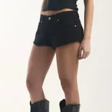 Short de denim negro con bolsillos traseros con solapa y detalle de alas bordadas con lentejuelas plateadas, tiro medio y bordes desmechados.