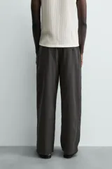 Pantalón de corte regular fit confeccionado en mezcla de algodón y lino. Presenta cintura elástica con cordón ajustable, cierre frontal con cremallera y botón, bolsillos laterales y bolsillo trasero de vivo con botón.
